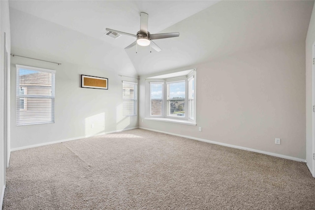 spare room with visible vents, baseboards, ceiling fan, vaulted ceiling, and carpet flooring