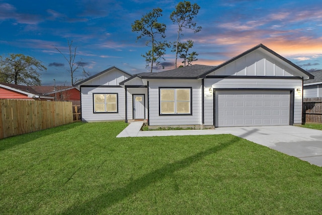 view of front of home featuring a lawn, driveway, fence, board and batten siding, and an attached garage