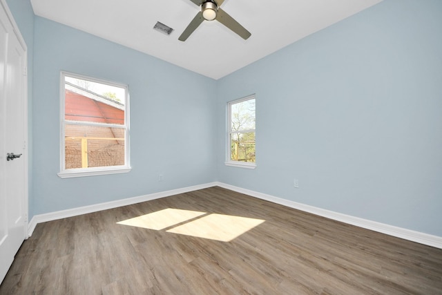 spare room with wood finished floors, a ceiling fan, baseboards, and visible vents