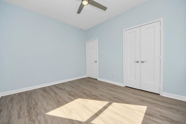 unfurnished bedroom with ceiling fan, a closet, baseboards, and wood finished floors
