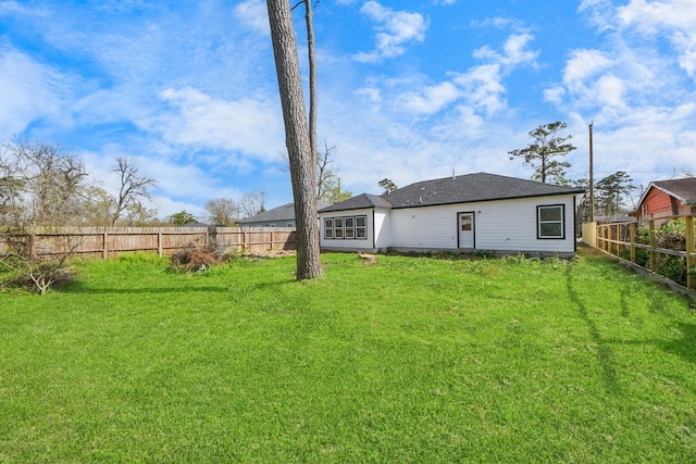 rear view of property featuring a fenced backyard and a yard