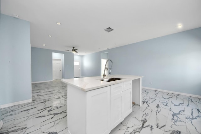 kitchen featuring marble finish floor, a sink, open floor plan, white cabinets, and baseboards