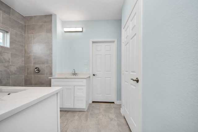 full bath with a tile shower and vanity