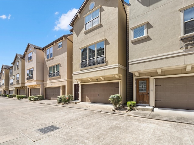 view of front of property with an attached garage, a residential view, driveway, and stucco siding