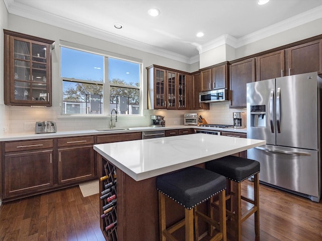 kitchen with crown molding, a kitchen breakfast bar, appliances with stainless steel finishes, and a sink