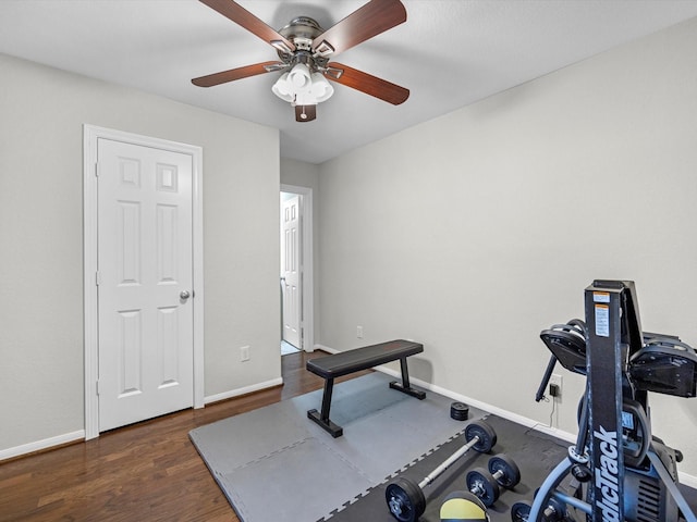 workout room featuring dark wood finished floors, a ceiling fan, and baseboards