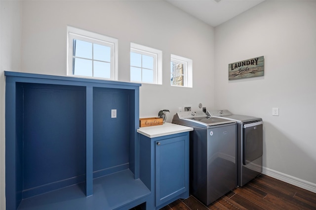 clothes washing area featuring dark wood-type flooring, cabinet space, baseboards, and washer and clothes dryer