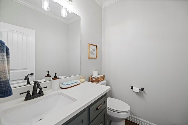 bathroom with baseboards, vanity, toilet, and crown molding