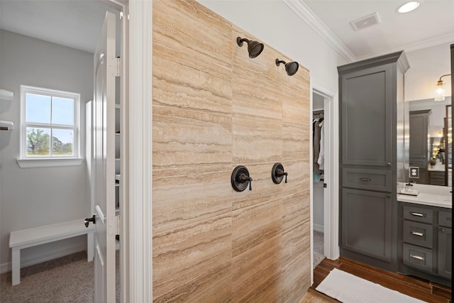 bathroom with vanity, baseboards, visible vents, tiled shower, and ornamental molding