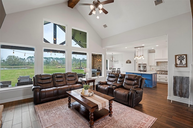 living area featuring visible vents, dark wood-type flooring, high vaulted ceiling, and ceiling fan with notable chandelier