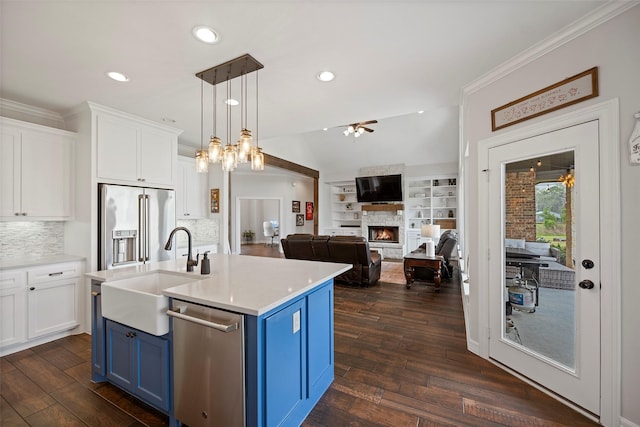 kitchen featuring a ceiling fan, blue cabinetry, a sink, stainless steel appliances, and white cabinets