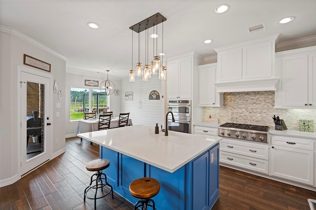 kitchen with a kitchen bar, light countertops, white cabinets, stainless steel appliances, and a sink