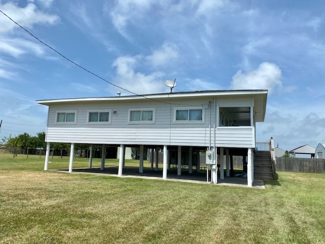 rear view of property with a yard, a patio, stairs, and fence