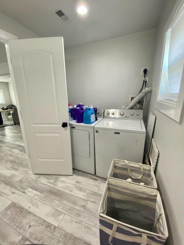 washroom with washing machine and clothes dryer, visible vents, laundry area, and wood tiled floor