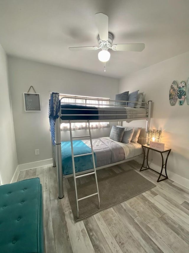 bedroom featuring a ceiling fan, baseboards, and wood finished floors