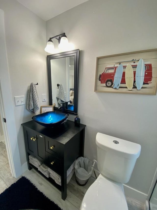 bathroom with baseboards, toilet, wood finished floors, and vanity