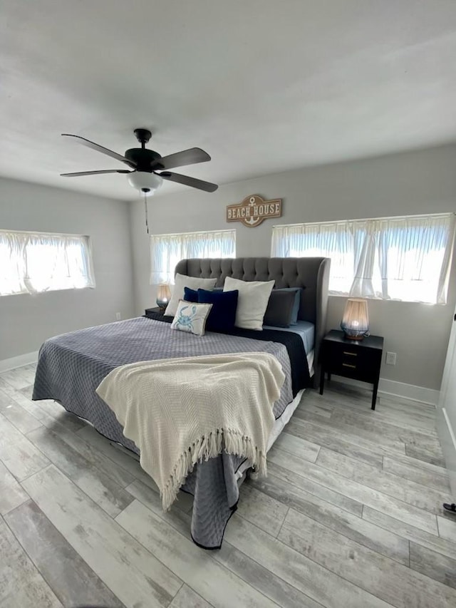 bedroom with a ceiling fan, baseboards, and wood finished floors