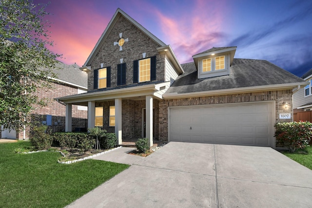 traditional-style home featuring brick siding, concrete driveway, covered porch, a lawn, and an attached garage