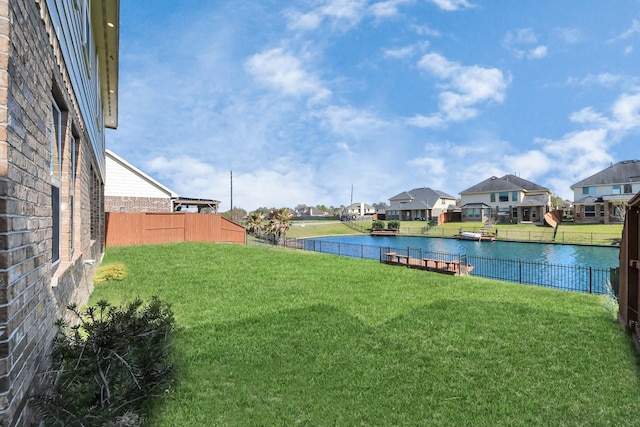 view of yard featuring fence, a water view, and a residential view