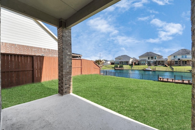 view of yard featuring a residential view, a water view, a patio area, and fence