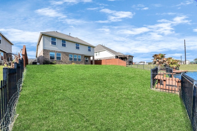 rear view of property with a yard and a fenced backyard