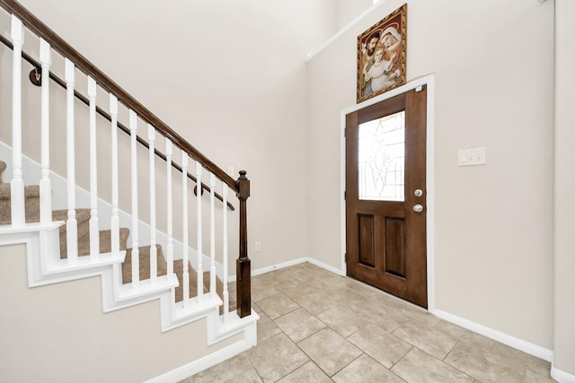 foyer entrance with light tile patterned floors, baseboards, and stairs