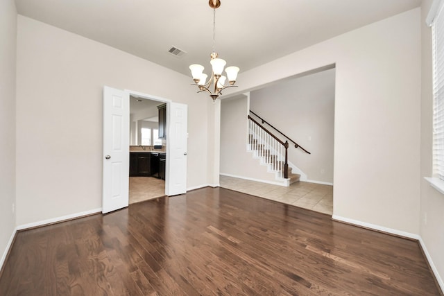 interior space featuring visible vents, baseboards, stairway, wood finished floors, and a notable chandelier