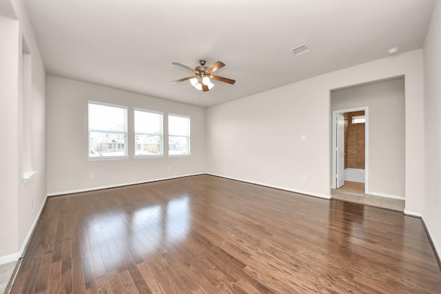 unfurnished room featuring a ceiling fan, wood finished floors, visible vents, and baseboards