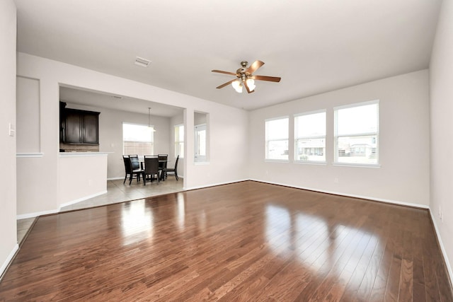 unfurnished living room featuring visible vents, baseboards, a ceiling fan, and wood finished floors