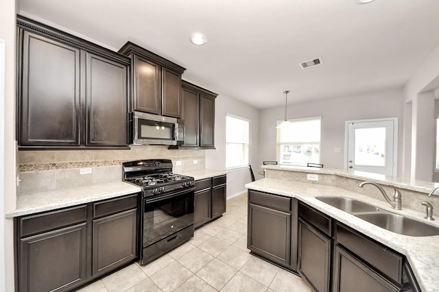 kitchen with visible vents, a sink, stainless steel microwave, tasteful backsplash, and black range with gas cooktop