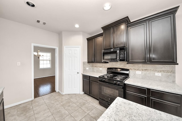 kitchen featuring stainless steel microwave, black gas stove, visible vents, decorative backsplash, and a notable chandelier