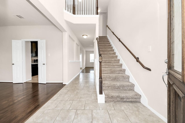 foyer featuring tile patterned flooring, stairway, baseboards, and visible vents