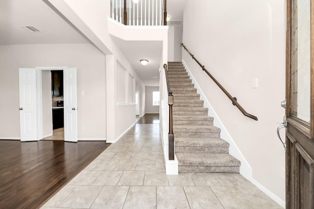 tiled entryway featuring stairs, baseboards, and visible vents