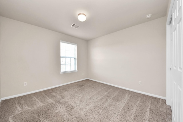 empty room with carpet, visible vents, and baseboards