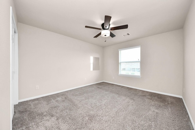 empty room with carpet flooring, a ceiling fan, visible vents, and baseboards