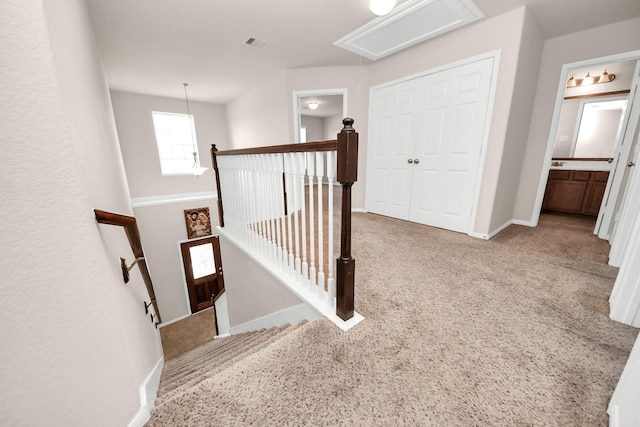 hall with visible vents, an upstairs landing, carpet flooring, baseboards, and attic access