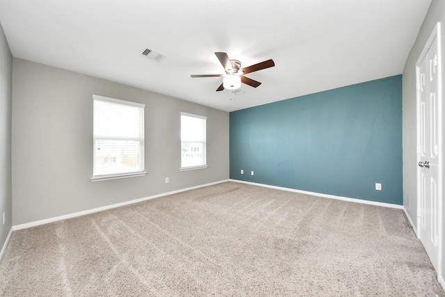 unfurnished room with carpet flooring, baseboards, visible vents, and ceiling fan