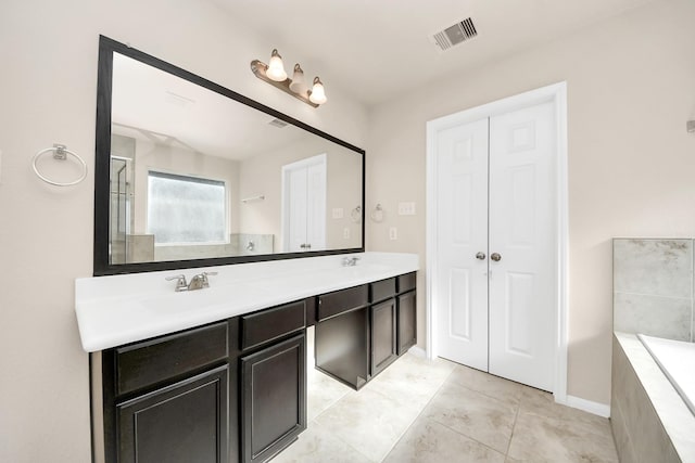 bathroom featuring double vanity, a relaxing tiled tub, visible vents, and a sink