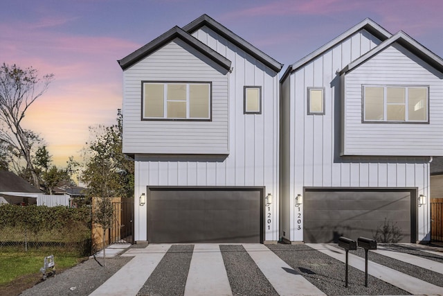 modern farmhouse style home with an attached garage, fence, board and batten siding, and driveway