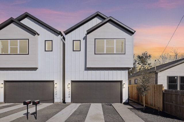 view of front facade with a garage, board and batten siding, driveway, and fence