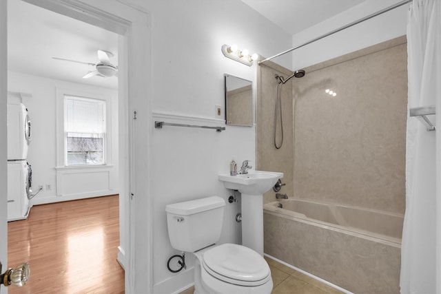 bathroom featuring toilet, stacked washer and dryer, bathing tub / shower combination, wood finished floors, and a ceiling fan