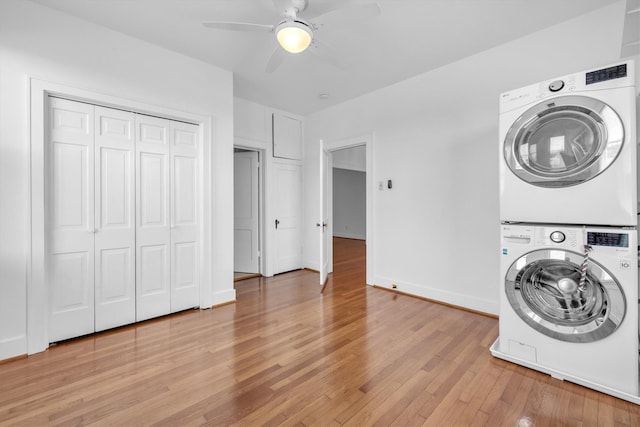 laundry room featuring light wood finished floors, stacked washer / dryer, baseboards, laundry area, and a ceiling fan