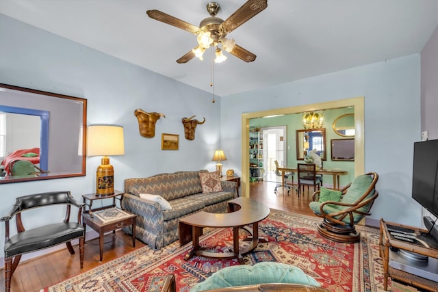 living room featuring ceiling fan with notable chandelier and wood finished floors