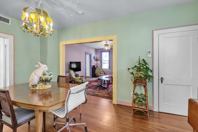 dining space featuring baseboards, wood finished floors, visible vents, and a chandelier