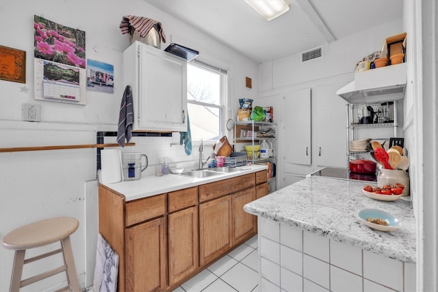kitchen featuring decorative backsplash, light countertops, light tile patterned flooring, and a sink