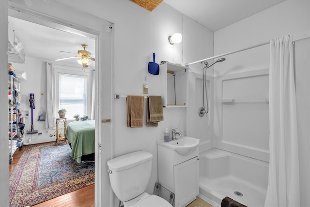 ensuite bathroom featuring vanity, wood finished floors, a ceiling fan, curtained shower, and toilet