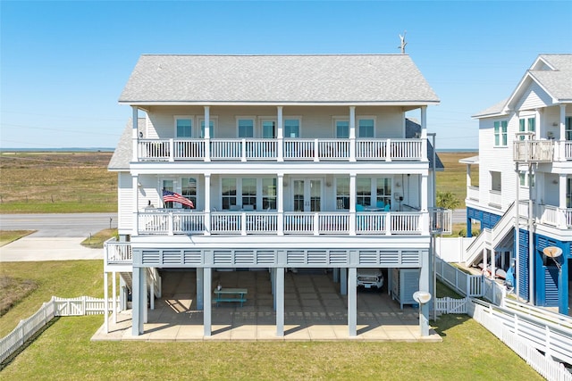 back of property featuring a fenced backyard, a balcony, a patio, and roof with shingles