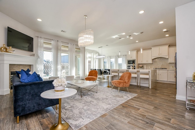 living area with recessed lighting, visible vents, an inviting chandelier, and dark wood-style floors