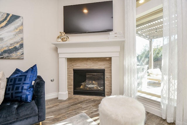 living room with baseboards, wood finished floors, and a tile fireplace