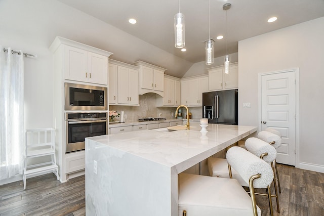 kitchen featuring a sink, stainless steel appliances, tasteful backsplash, and dark wood finished floors